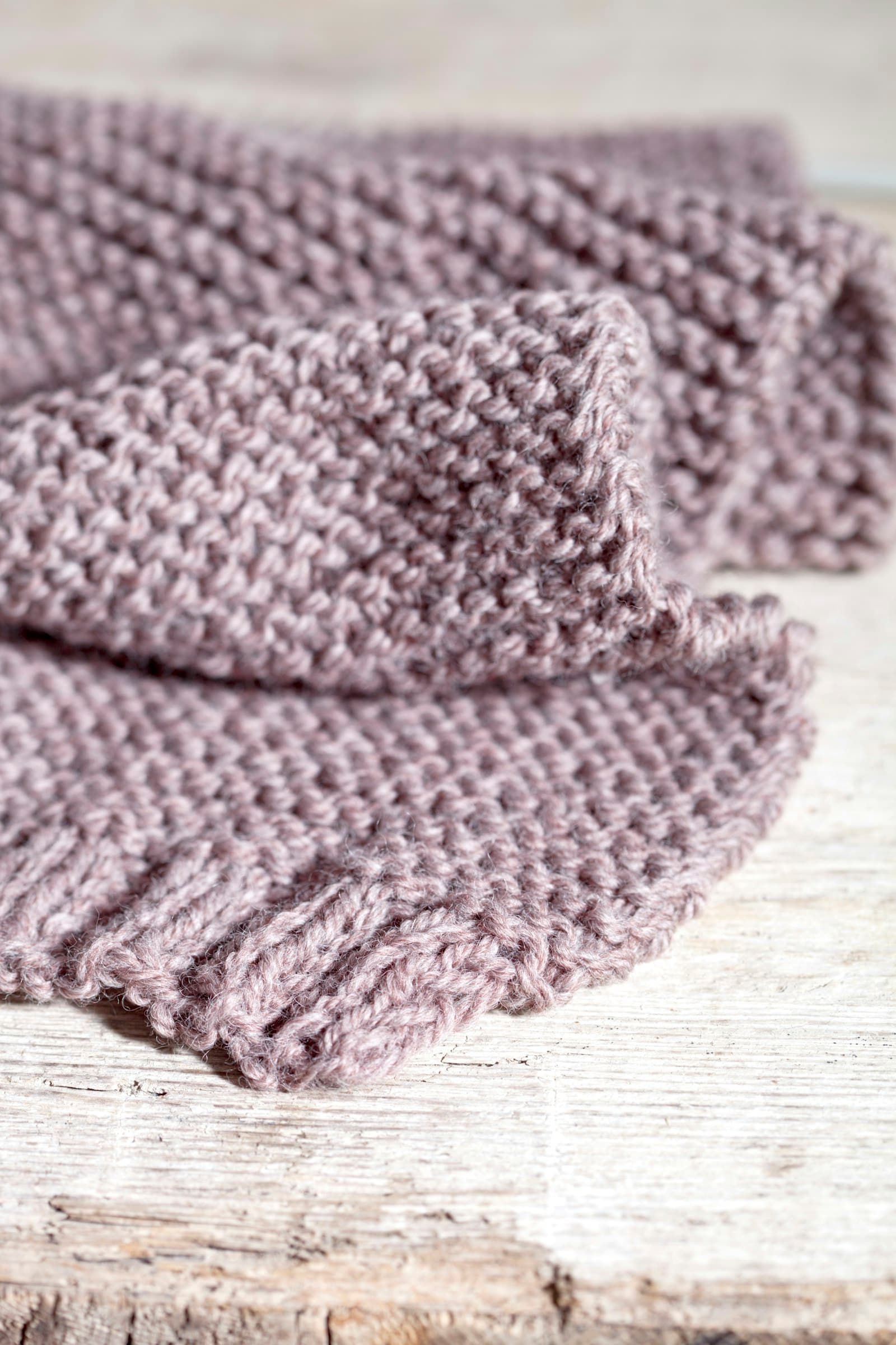 A close up of a knitted scarf on a wooden surface